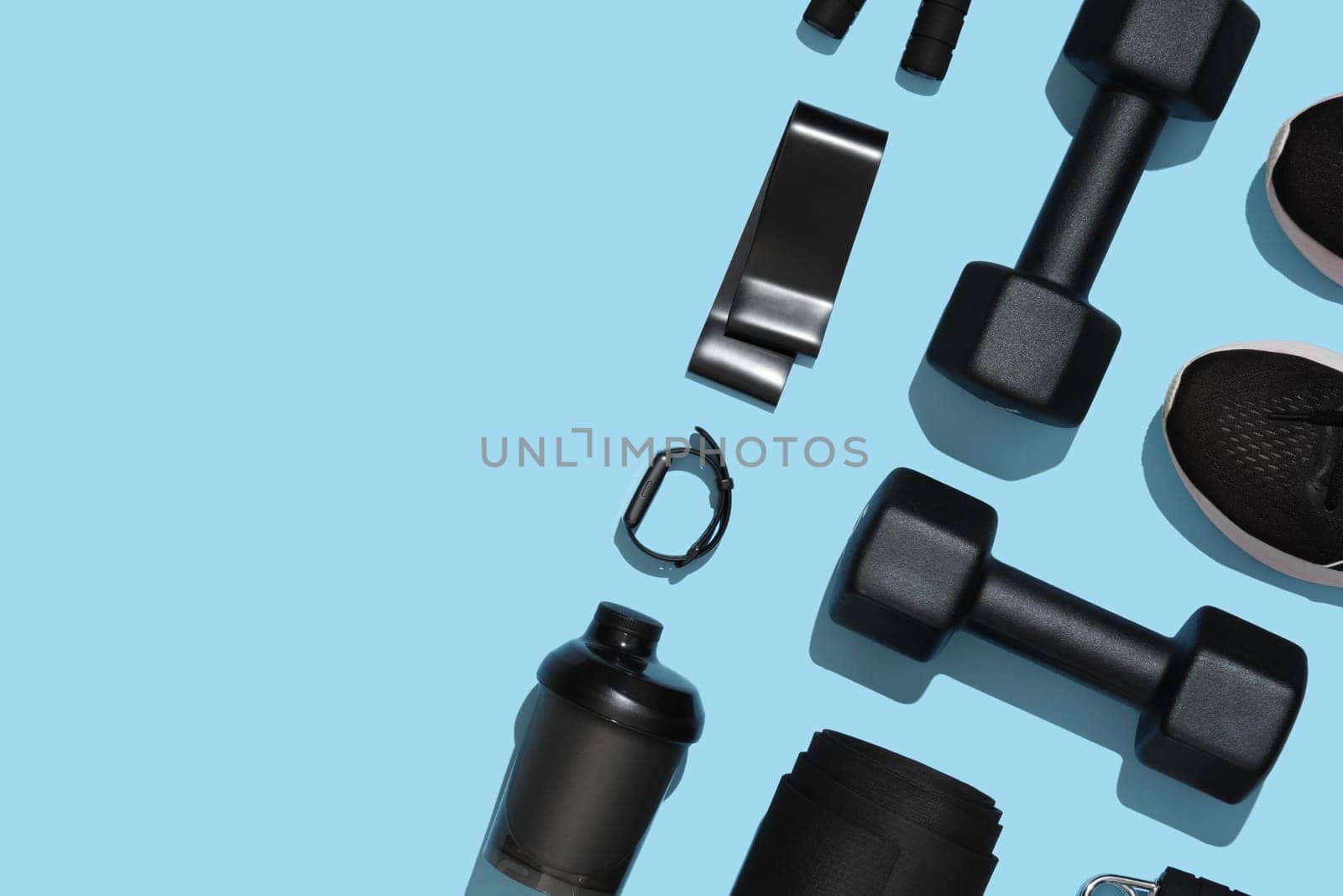 Black workout equipment for training at home on blue background. Fitness, sport items, healthy lifestyle concept. Copyspace