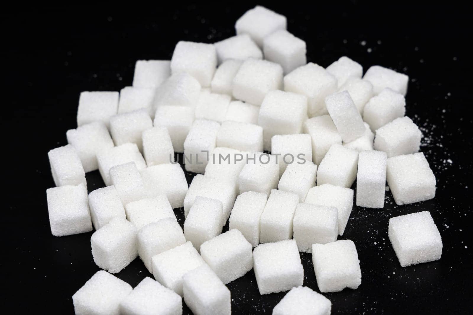 Cubes of white refined sugar on a black background. High quality photo