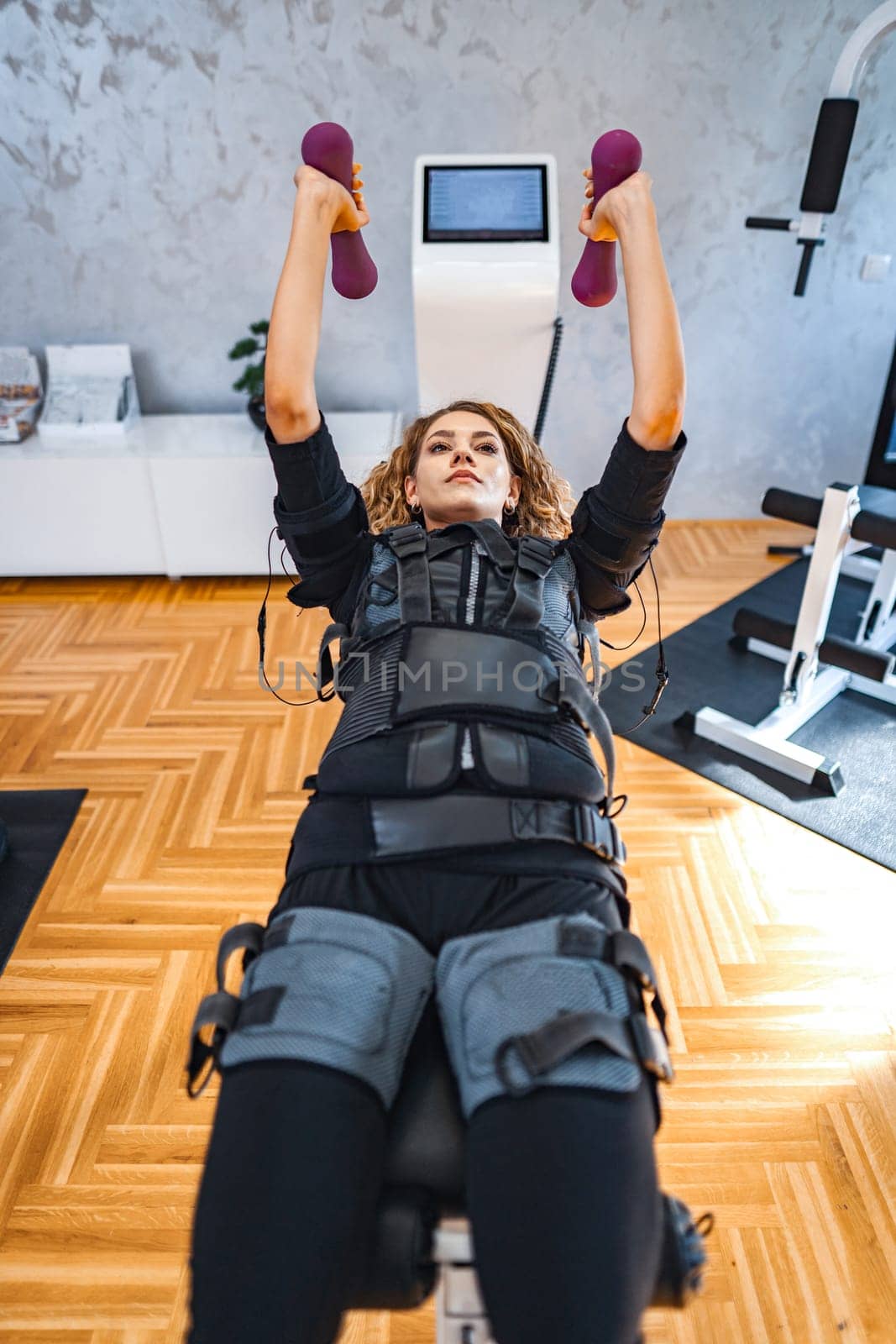 A woman engages in a strength workout using muscle stimulation technology.
