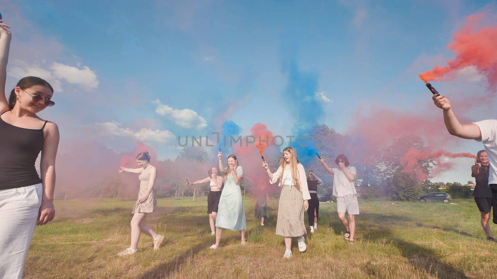 High school graduates enjoy a carefree summer day, celebrating their graduation with colorful smoke bombs in a grassy field