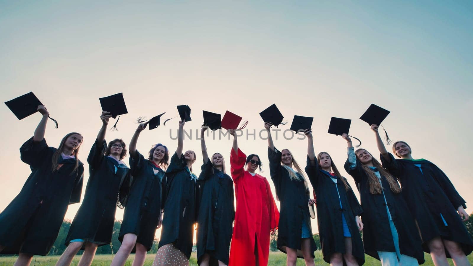Energetic students in graduation attire joyfully tossing mortarboards in the air to celebrate their academic achievement