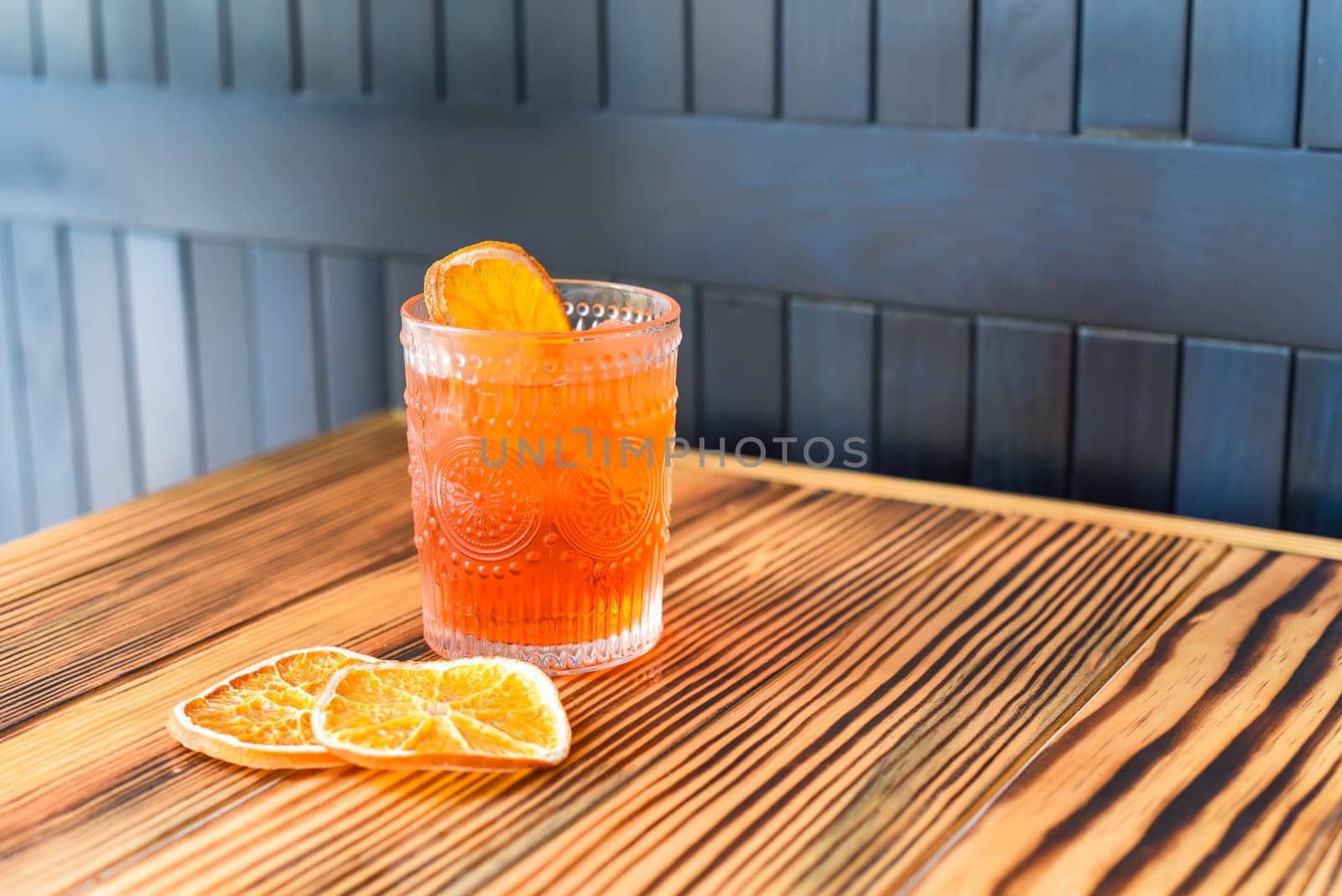 Alcohol cocktail Aperol Spritz with slise of orange on wooden table against dark wall with copy space