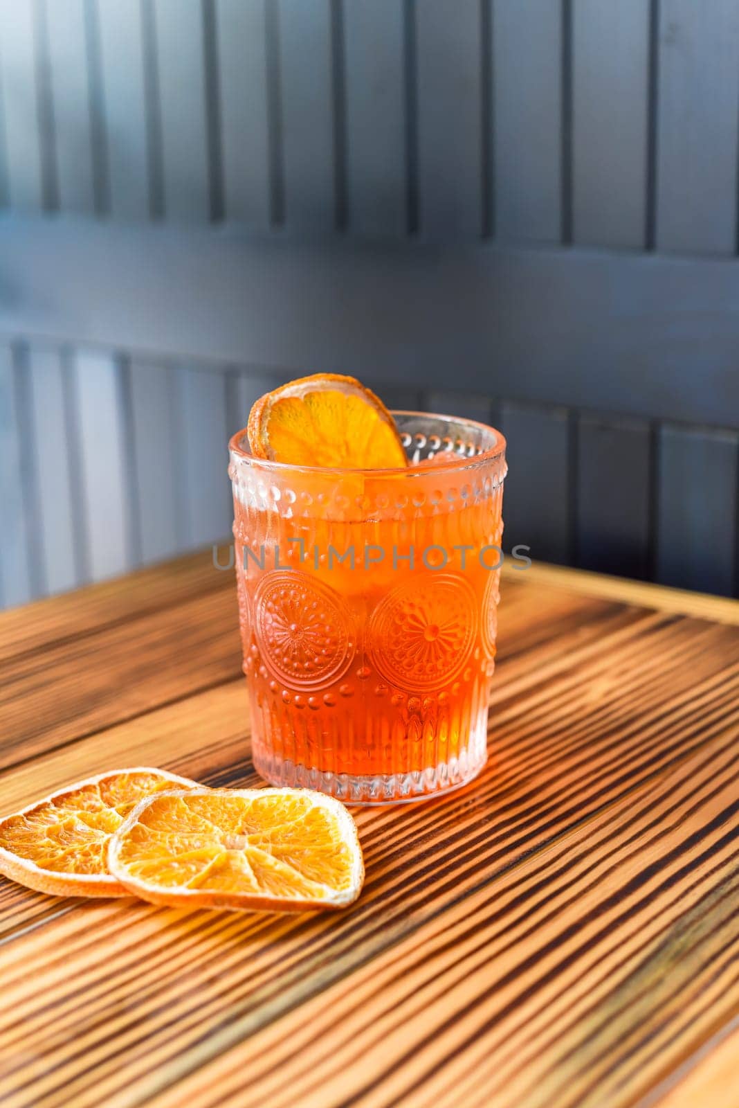 Alcohol cocktail Aperol Spritz with slise of orange on wooden table against dark wall with copy space