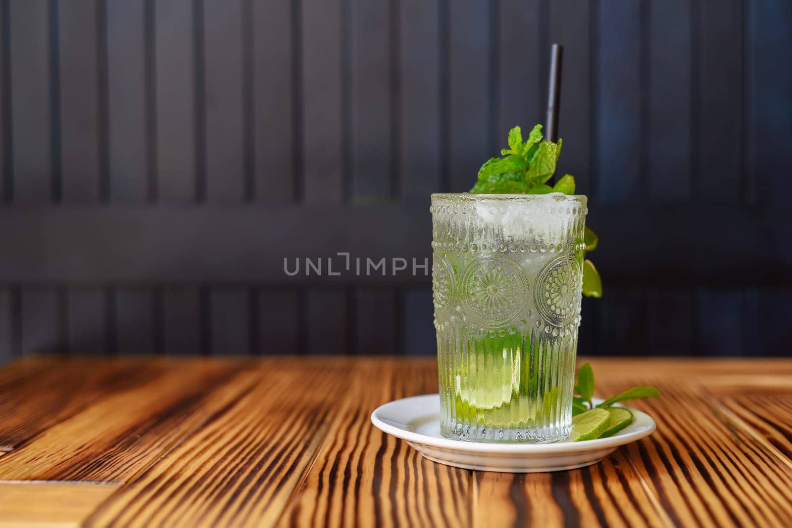 Alcohol cocktail Mojito on wooden table against dark wall with copy space