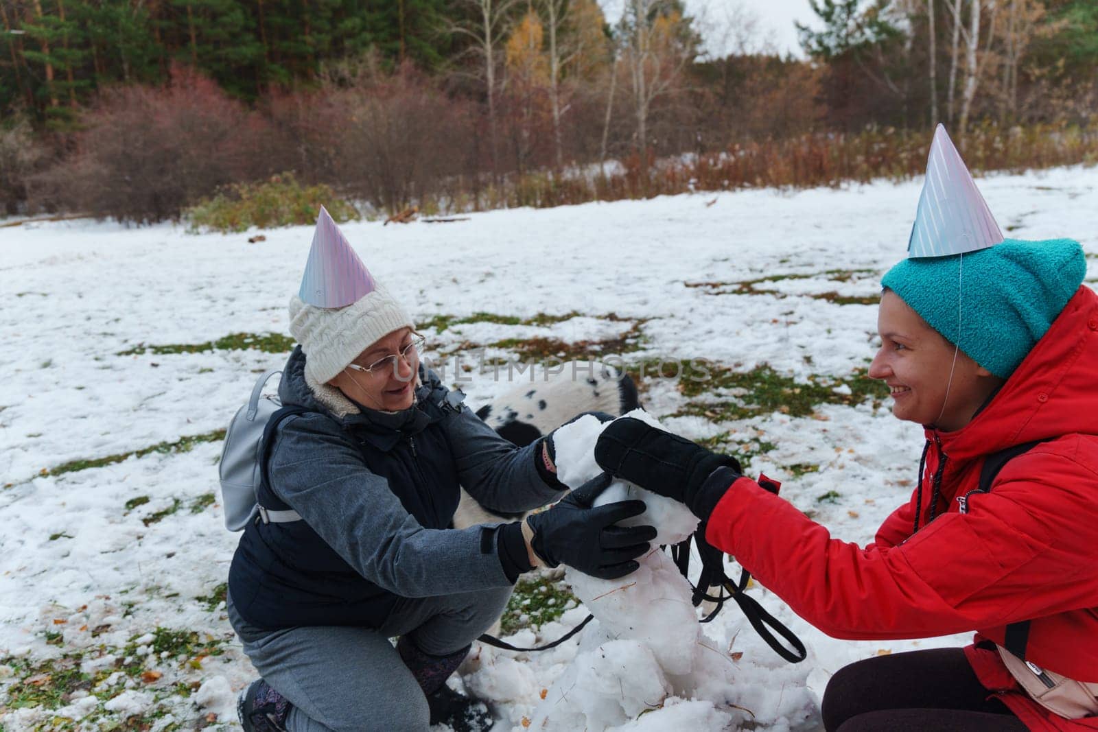 Joyful moments creating a snowman with friends in a snowy park during winter celebrations