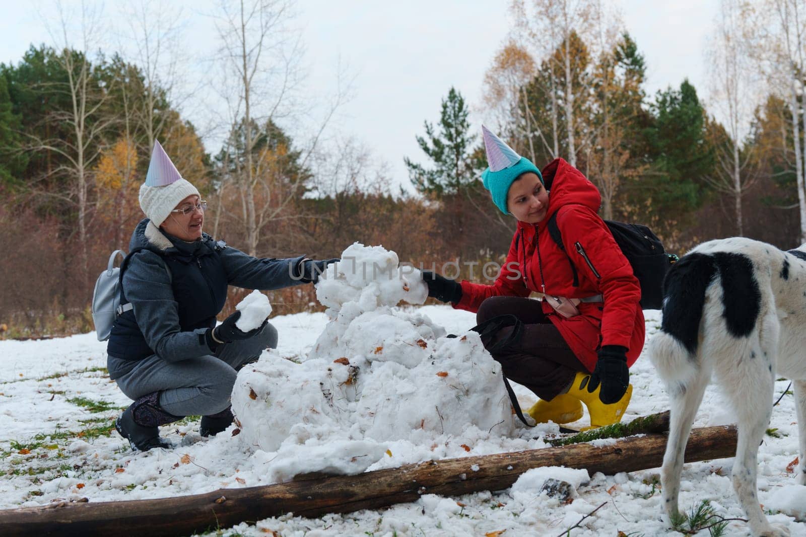 Laughter fills the air as cheerful friends create snowballs, donning festive hats in a snowy landscape.