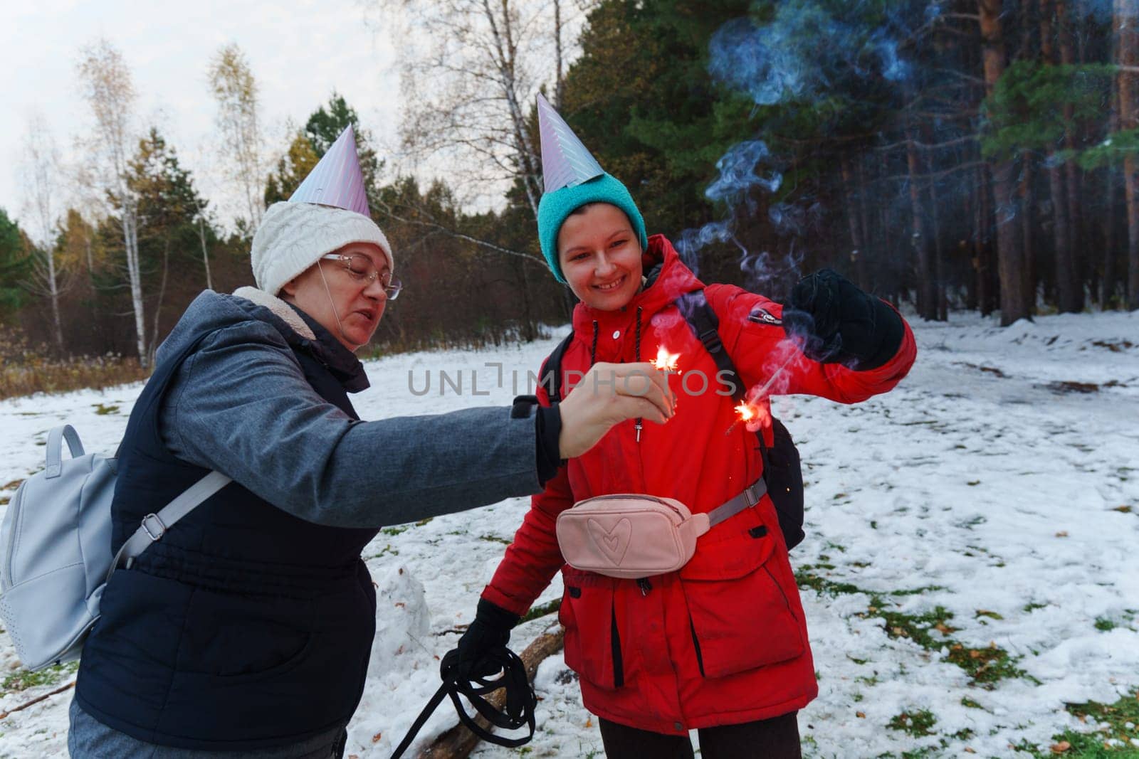 Celebration in the snowy forest with joyful individuals creating colorful sparks in winter