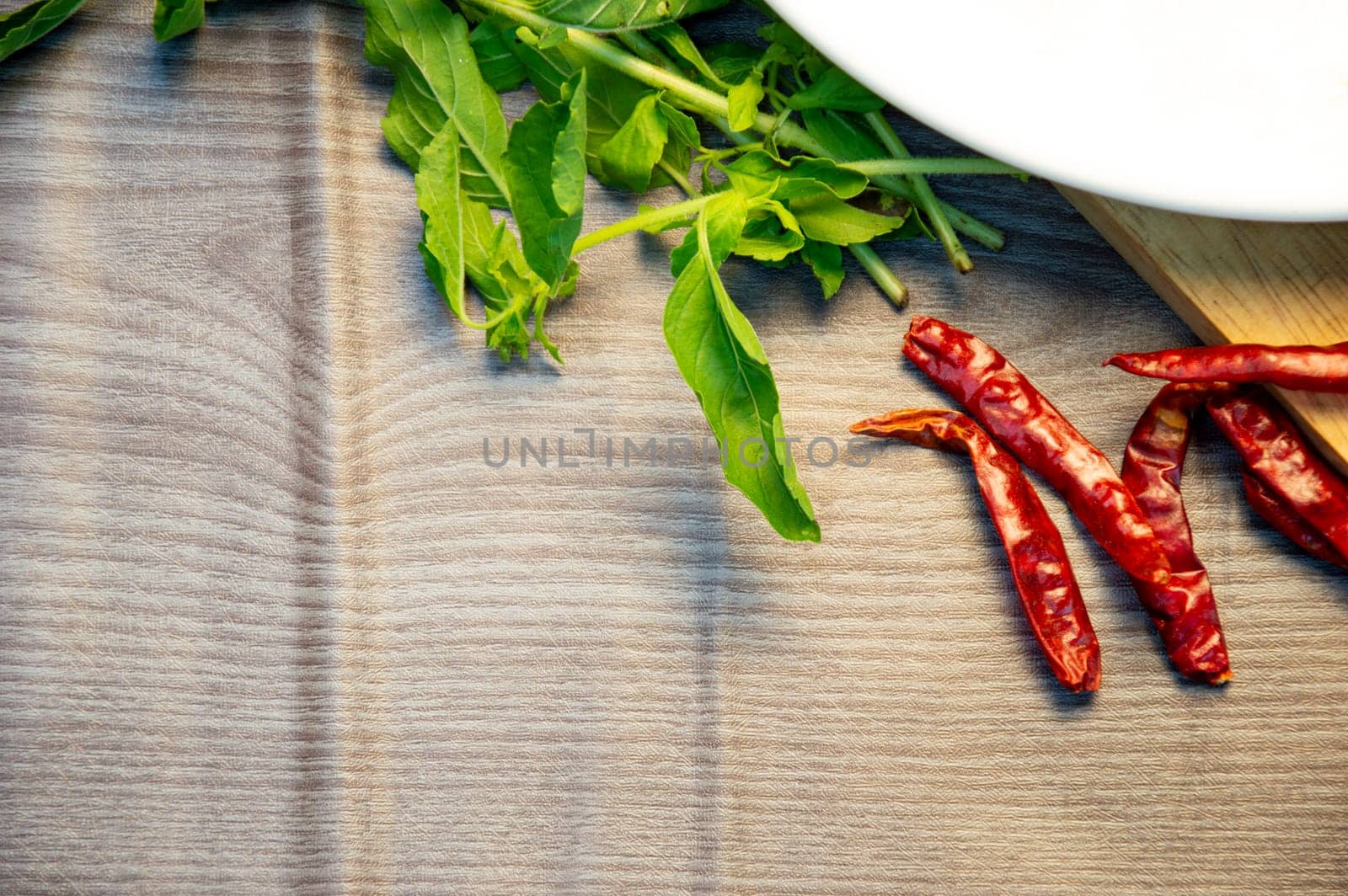Dried chillies, basil leaves on wooden background