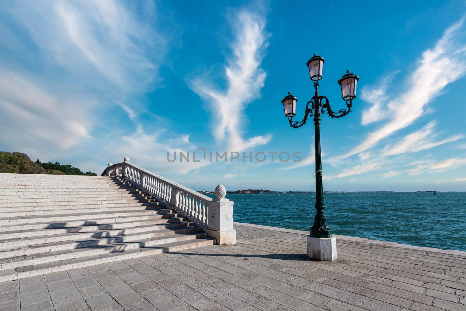 Italy, Venetian embankment in the afternoon. Historical lamp post on the quay and bridge.