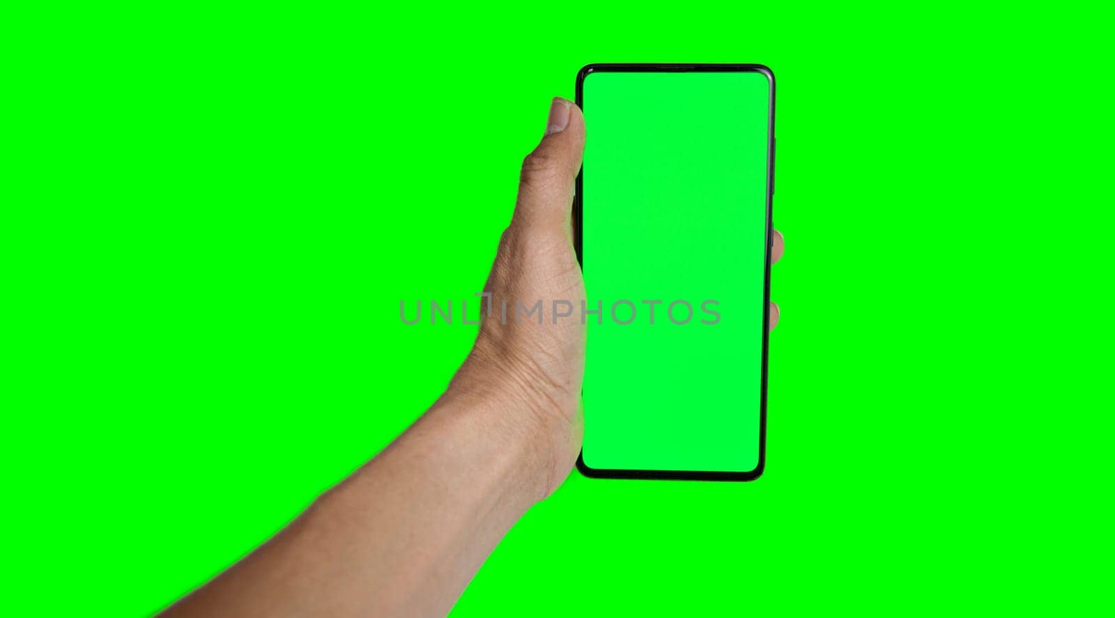 hand holding a green smartphone on a green background by boonruen