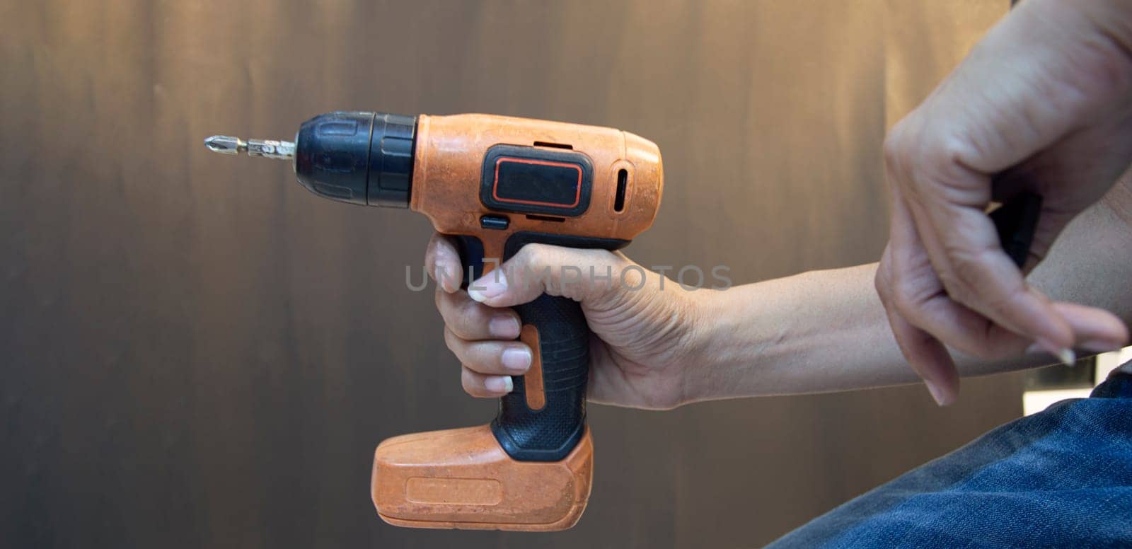 artisan who is holding orange electric screwdriver by boonruen