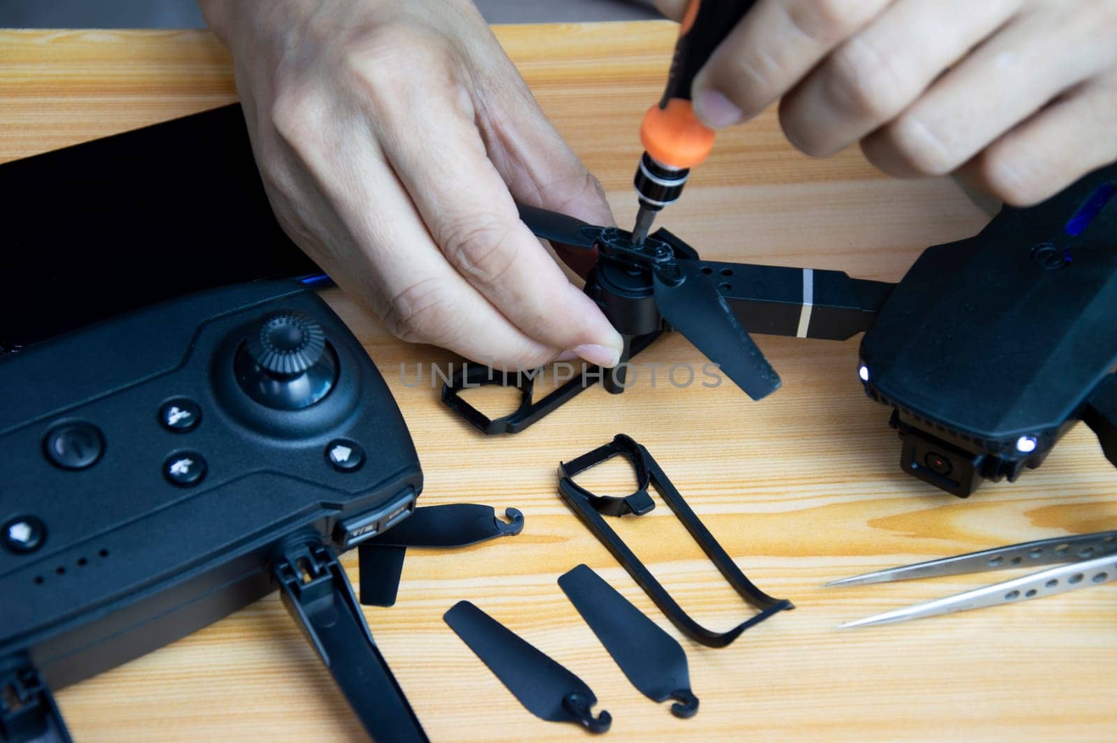 Professional mechanic repairing a drone with a small screwdriver on the table with various tools in modern workshop by boonruen