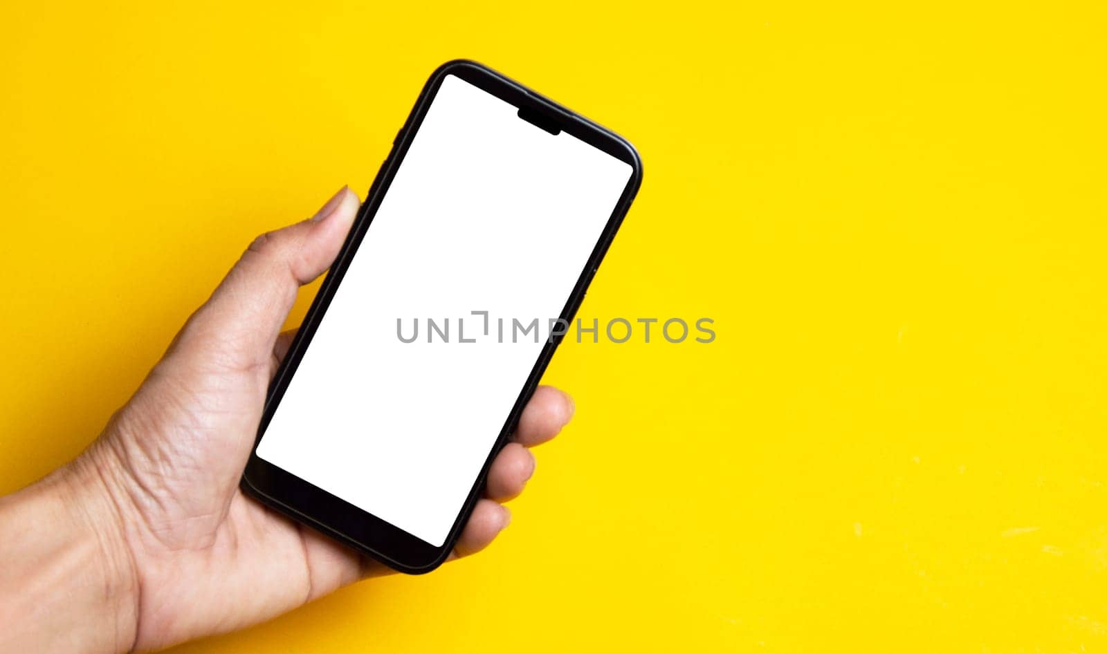 Hand holding a smartphone on a yellow background