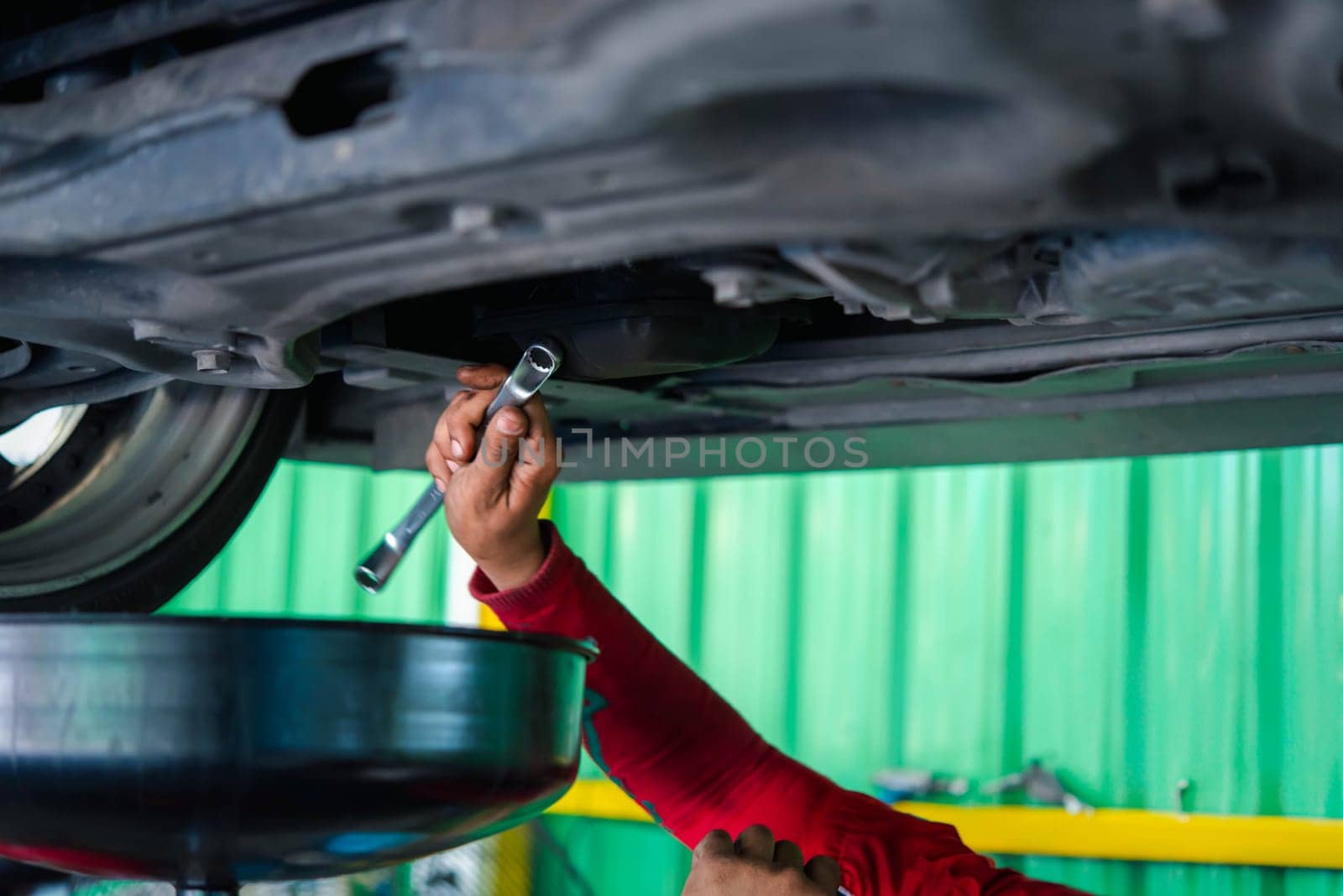 Car mechanic drain the old lubricant engine oil at car garage for changing the oil in a car engine