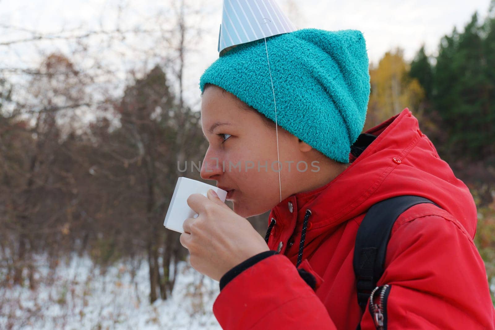 Celebrating friendship in a snowy forest with warm drinks and playful hats during a winter gathering