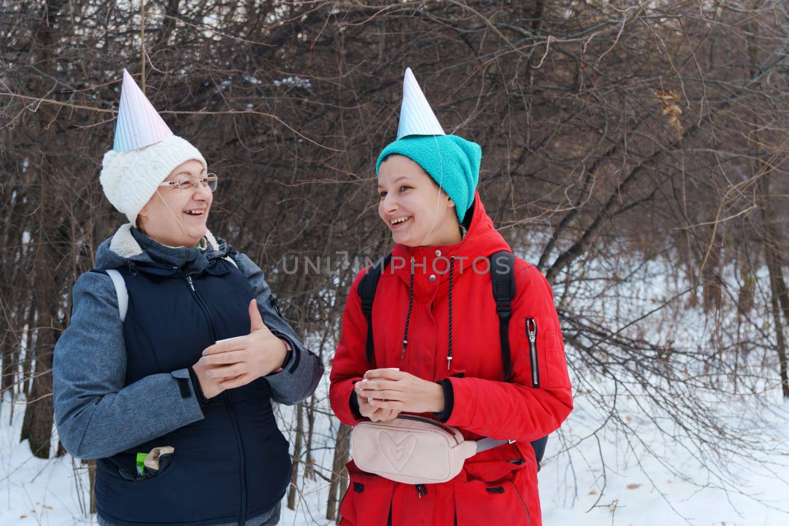 Winter celebration in the forest with friends wearing festive hats and enjoying warm drinks