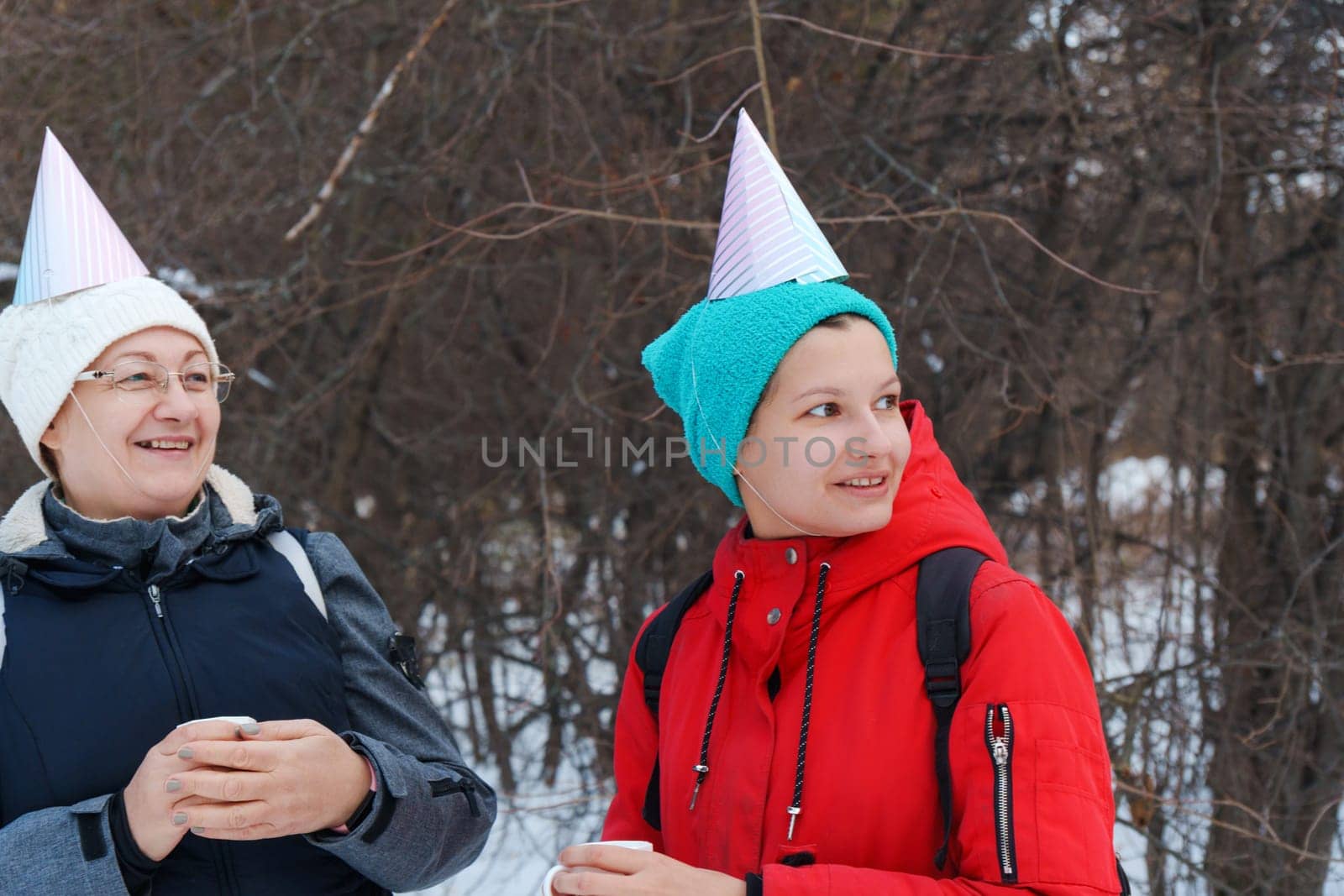 Winter celebration in the forest with friends wearing festive hats and enjoying warm drinks