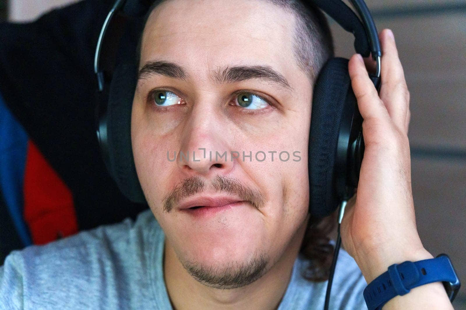 A man listens to music with deep concentration, showcasing a thoughtful expression. He wears headphones