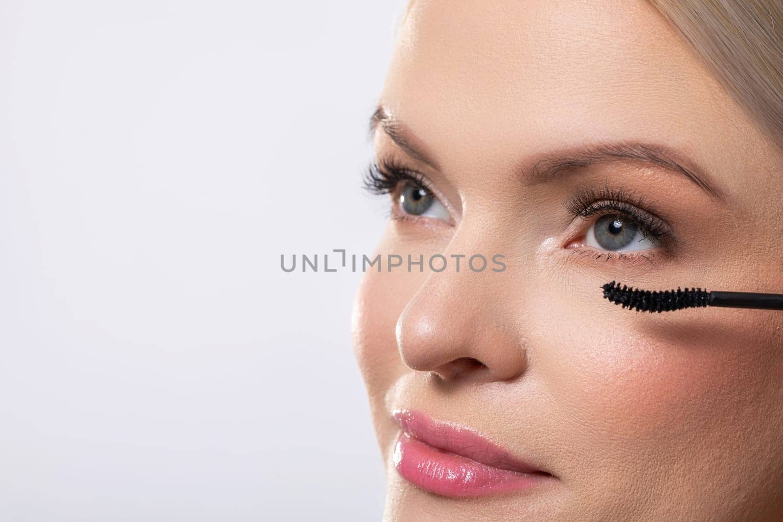 Closeup of a woman meticulously applying her mascara, showcasing her beauty, makeup skills, and elegant appearance