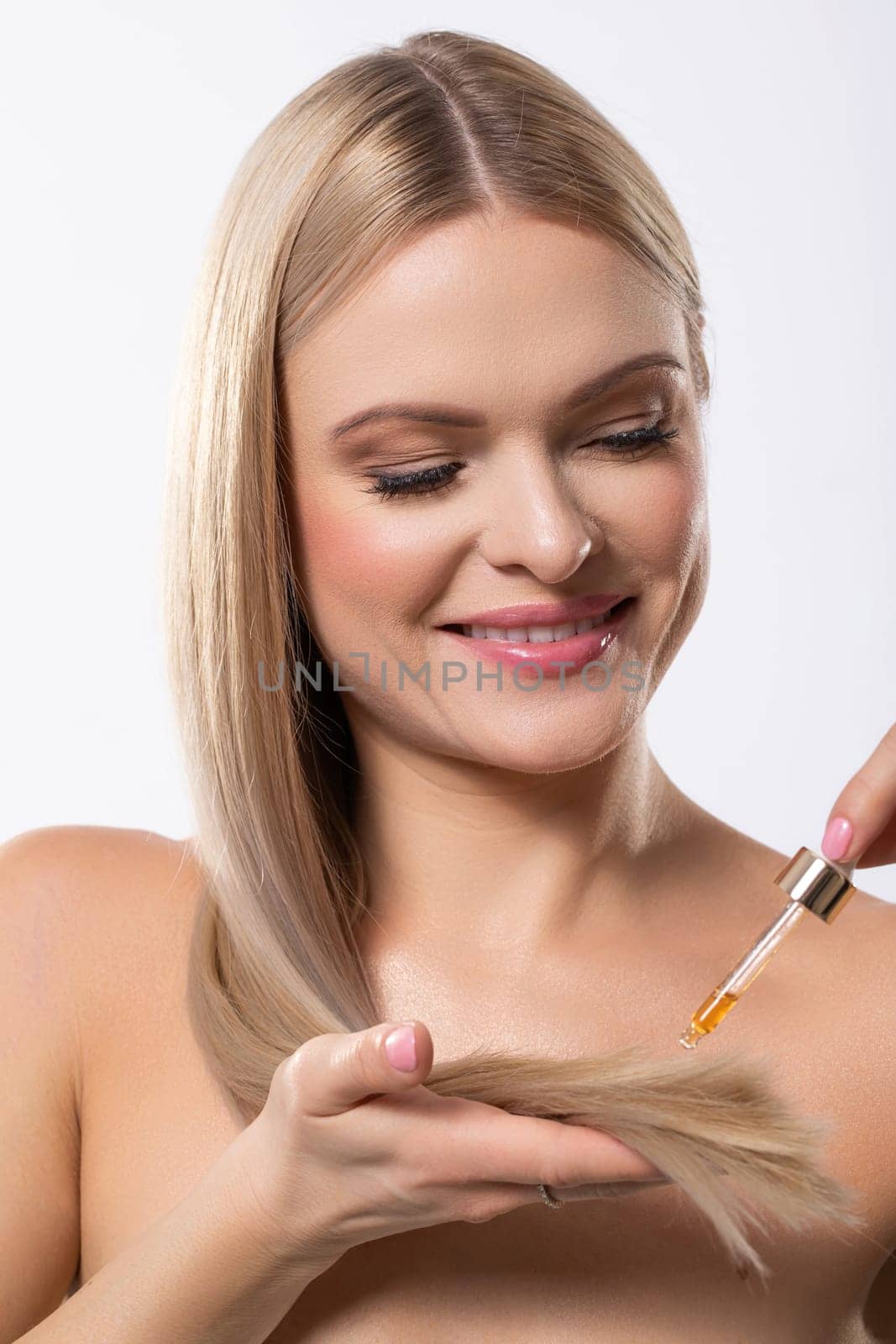 A woman gently applying nourishing oil to her hair, enhancing its revitalization, health, and glossy shine