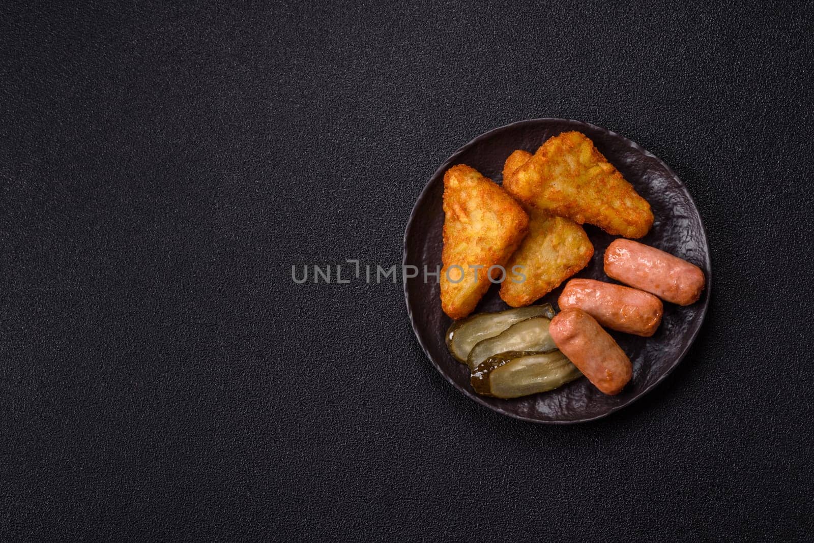 Hash browns with potatoes and onions, salt and spices on a dark concrete background