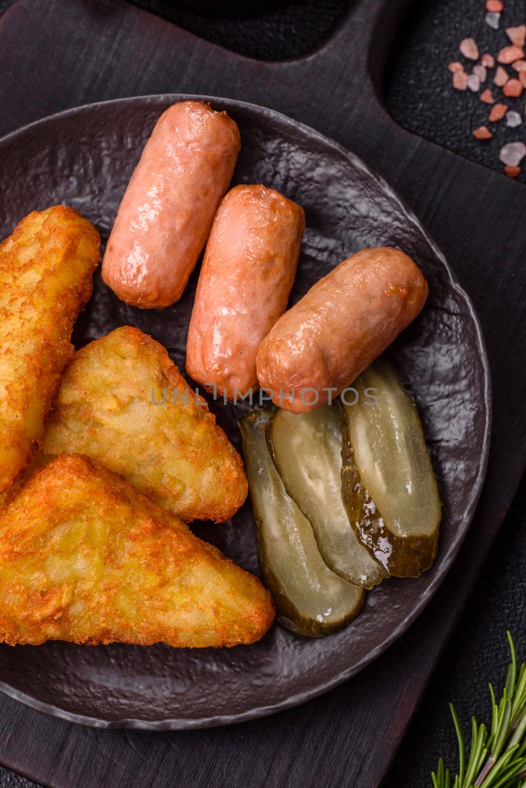 Hash browns with potatoes and onions, salt and spices on a dark concrete background