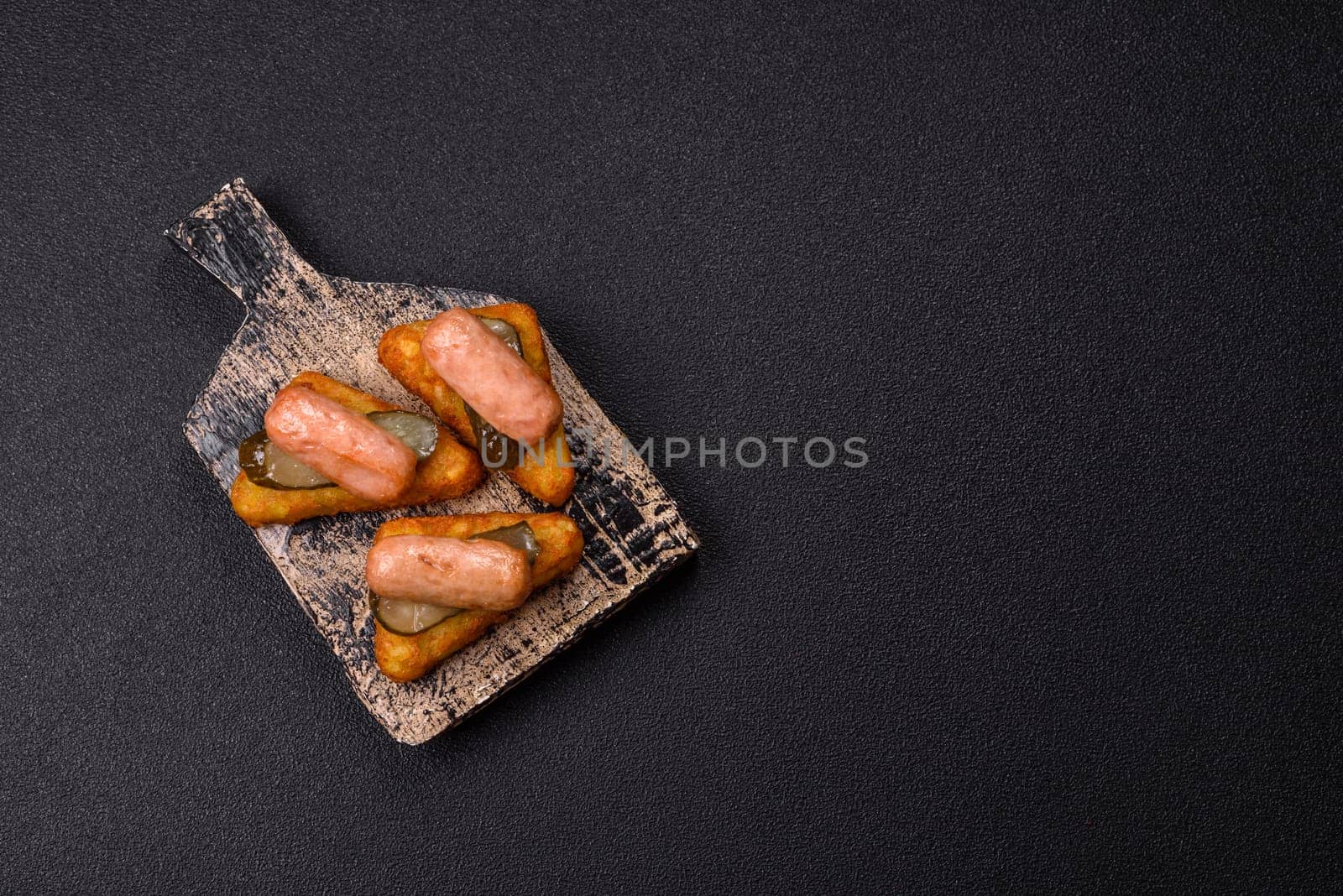 Hash browns with potatoes and onions, salt and spices on a dark concrete background