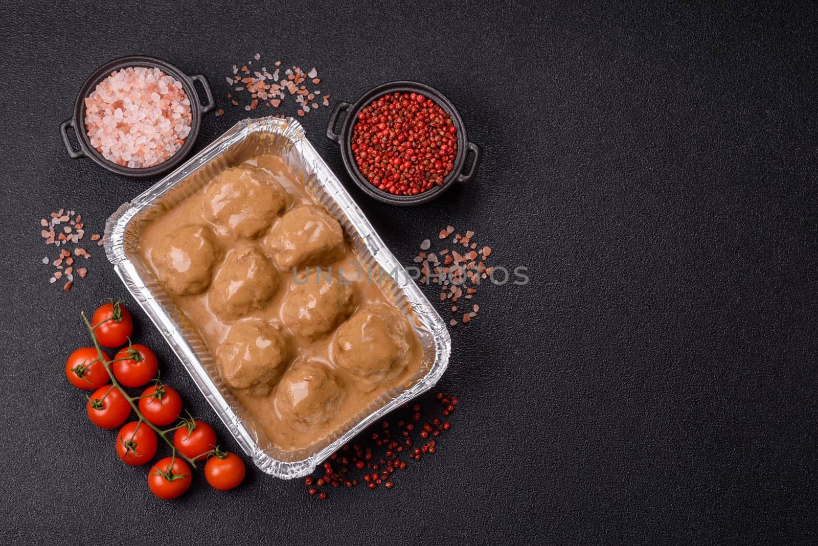 Meatballs with salt and spices in creamy caramel sauce on a dark concrete background