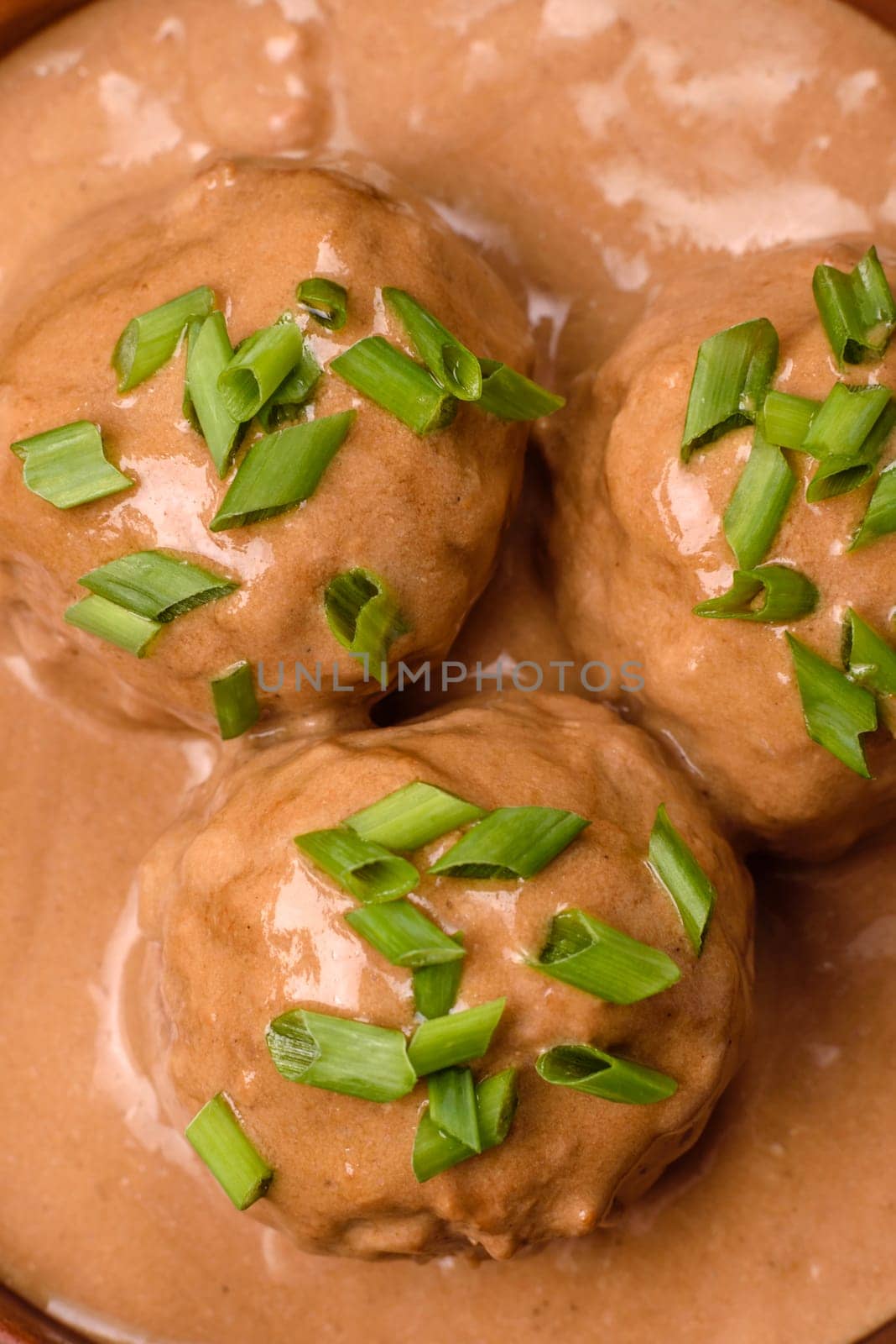 Meatballs with salt and spices in creamy caramel sauce on a dark concrete background