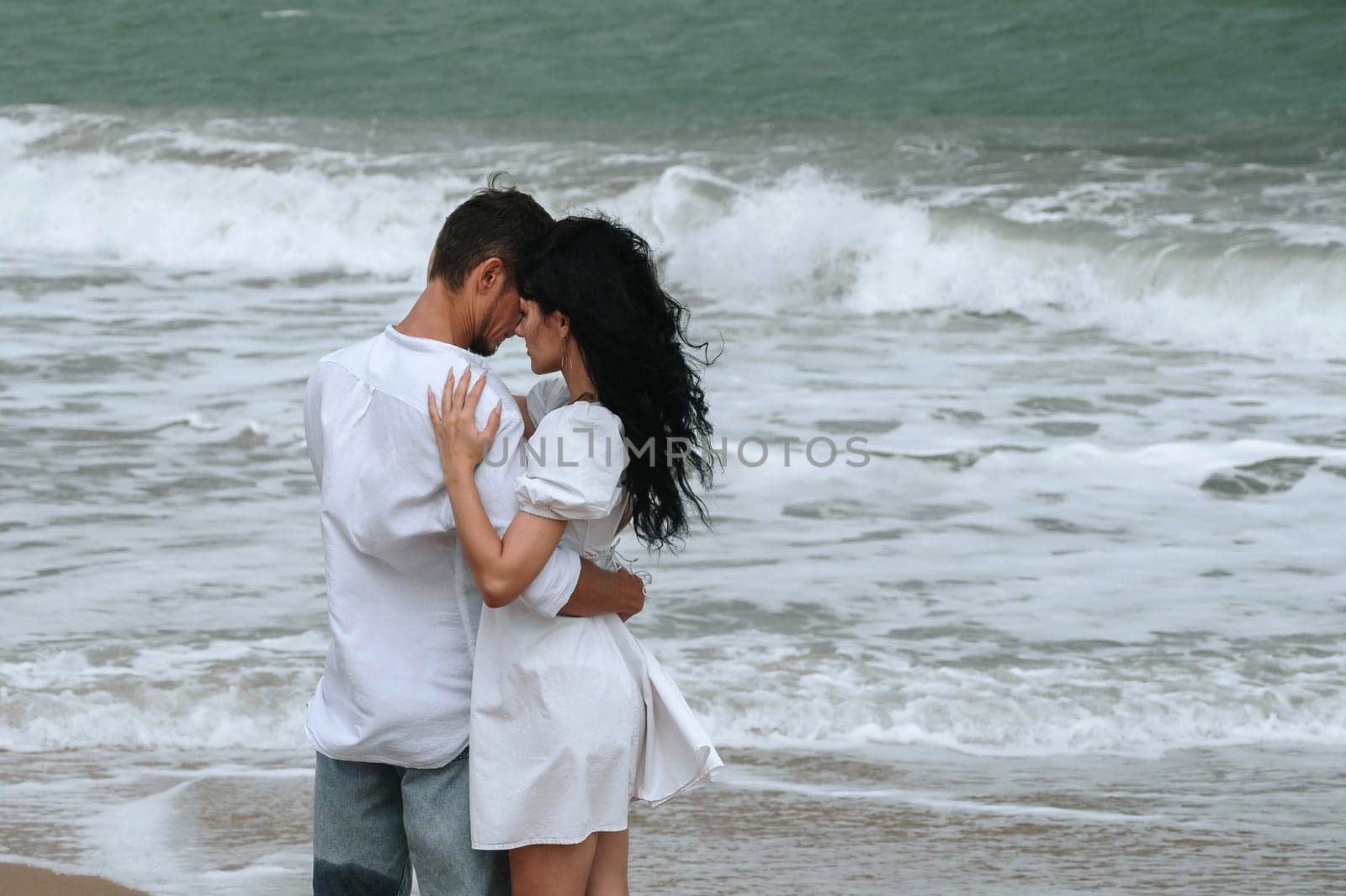 young beautiful couple in love hugging on the beach by the sea in summer