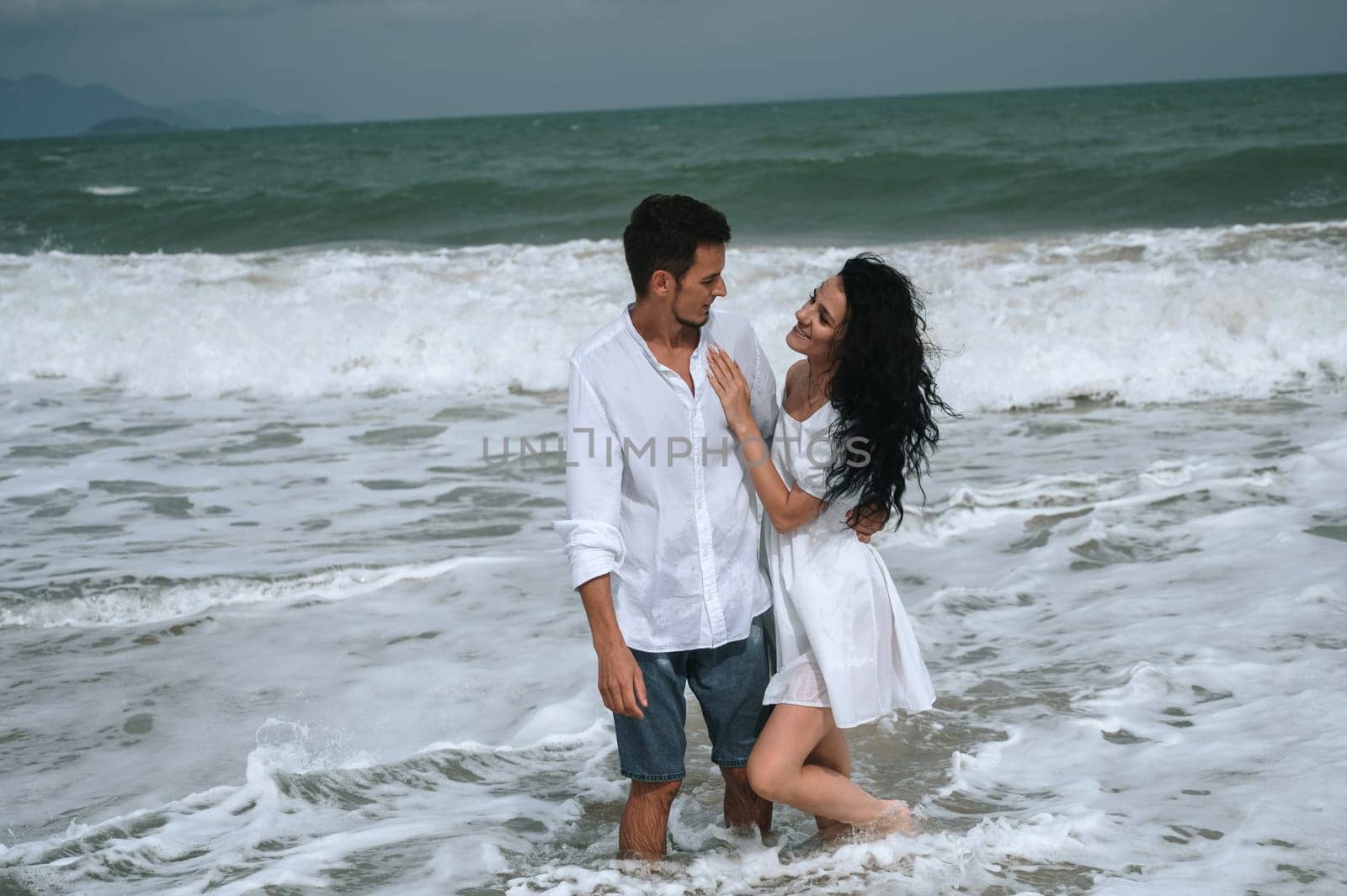 Happy young couple in love on the beach by the sea in summer