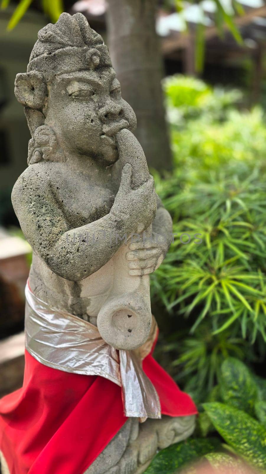Garden Gnome traditional stone statue situated in a tranquil tropical garden, surrounded by vibrant foliage and artistic decor, harmonizing with the natural beauty of its environment. Good for Background