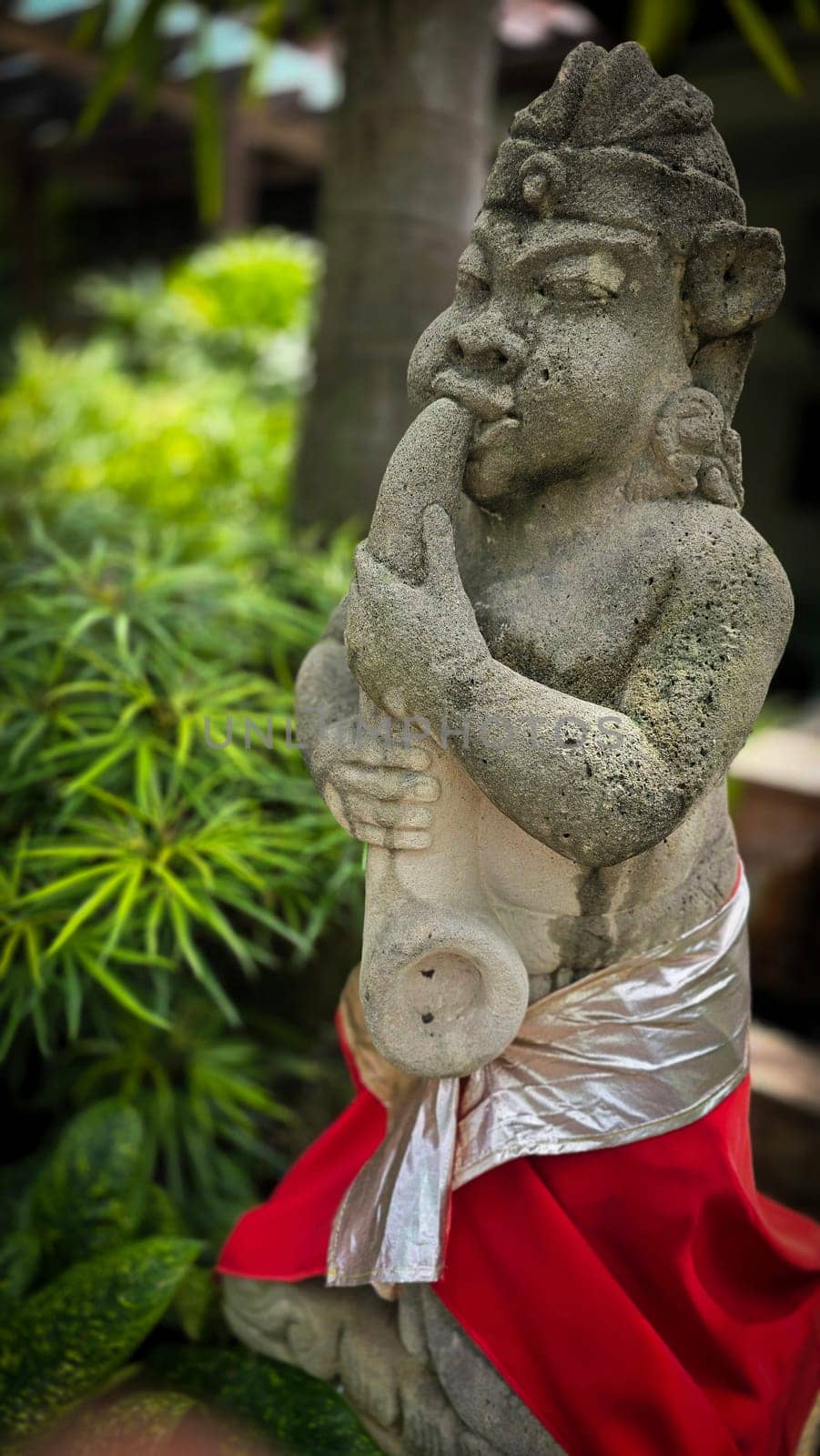 Garden Gnome traditional stone statue situated in a tranquil tropical garden, surrounded by vibrant foliage and artistic decor, harmonizing with the natural beauty of its environment. Good for Background