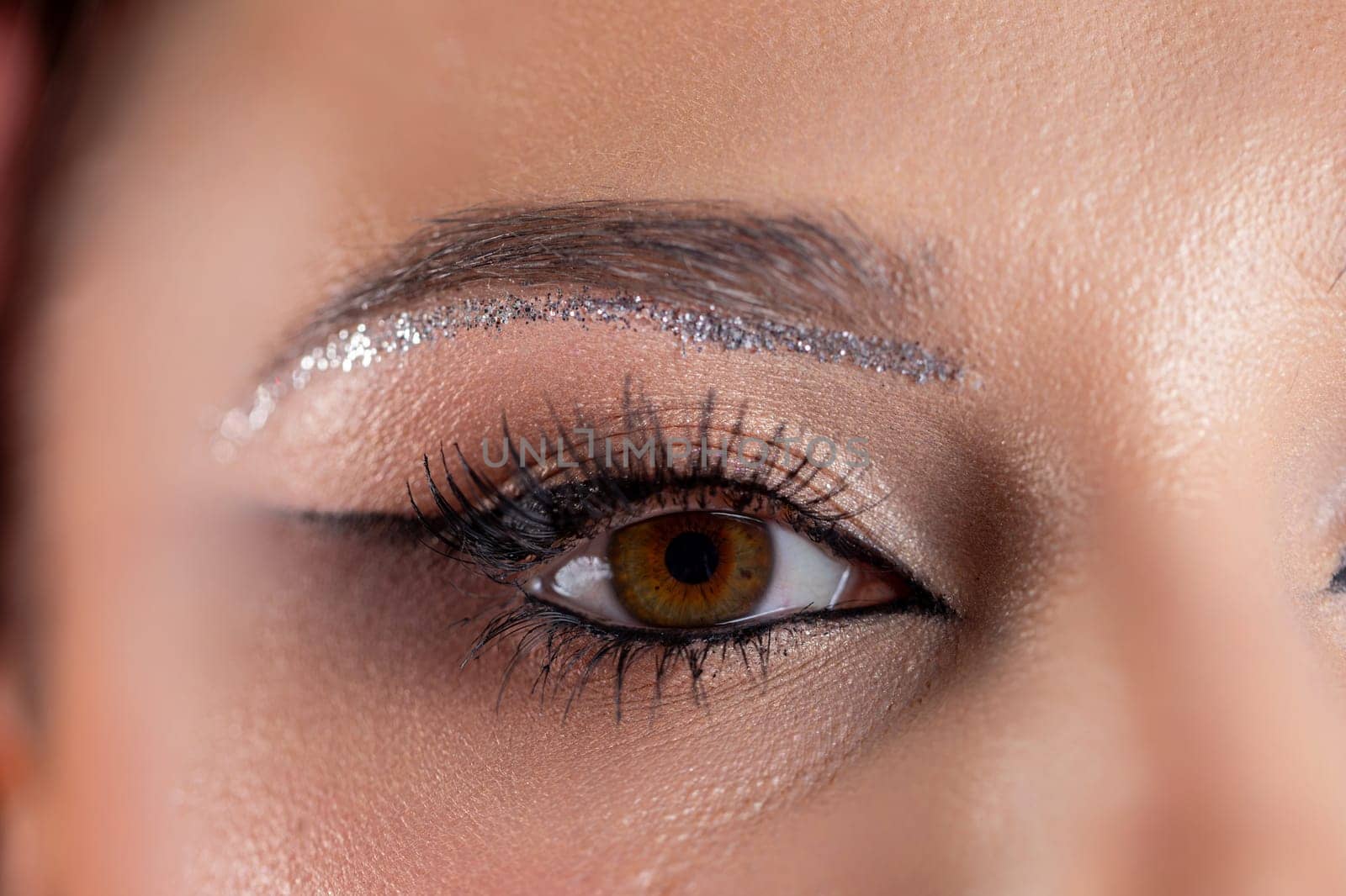 A stunning closeup of an eye reveals glamorous makeup artistry, featuring eyecatching sparkling accents