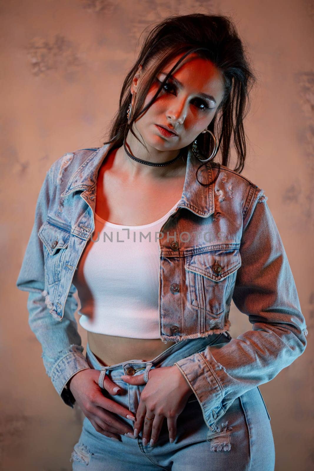 A fashionable young woman confidently poses in a stylish denim outfit paired with a chic crop top, exuding confidence