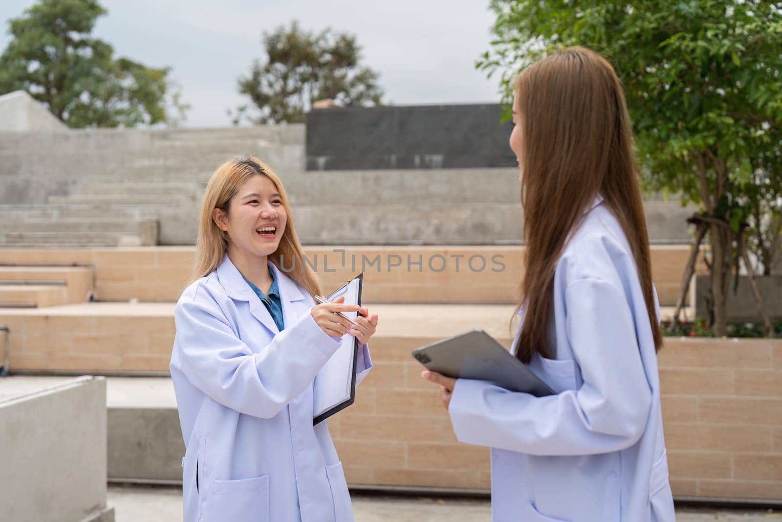 Two diverse female doctors joyfully discussing patient care outside a medical facility, emphasizing collaboration and a positive atmosphere in healthcare.