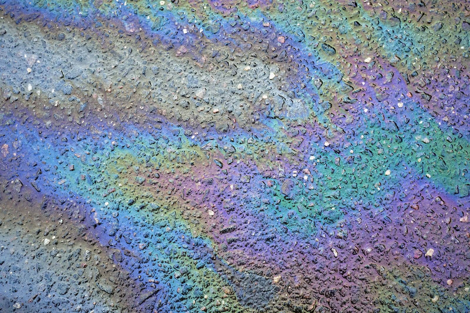 Close-up of multicolored fuel spills, revealing a rich backdrop of various shades on the roadway