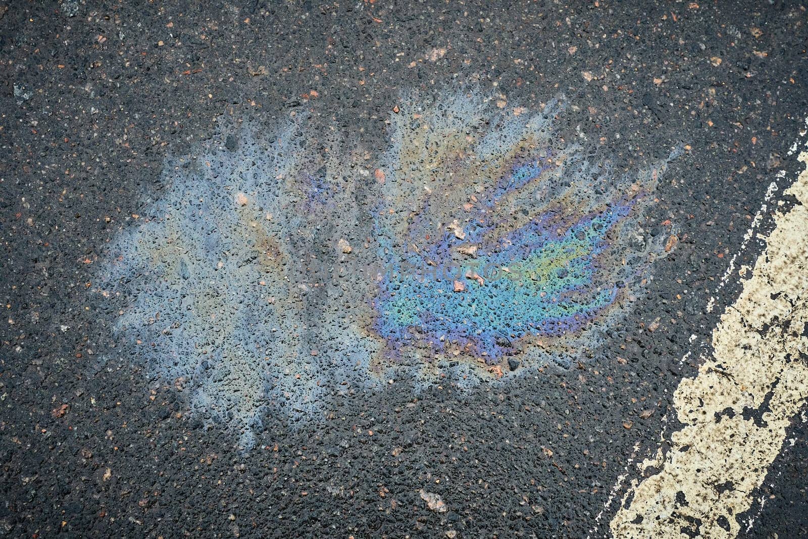 Damp surface in a parking spot, showing a fuel leak from a car, outlined with a white stripe