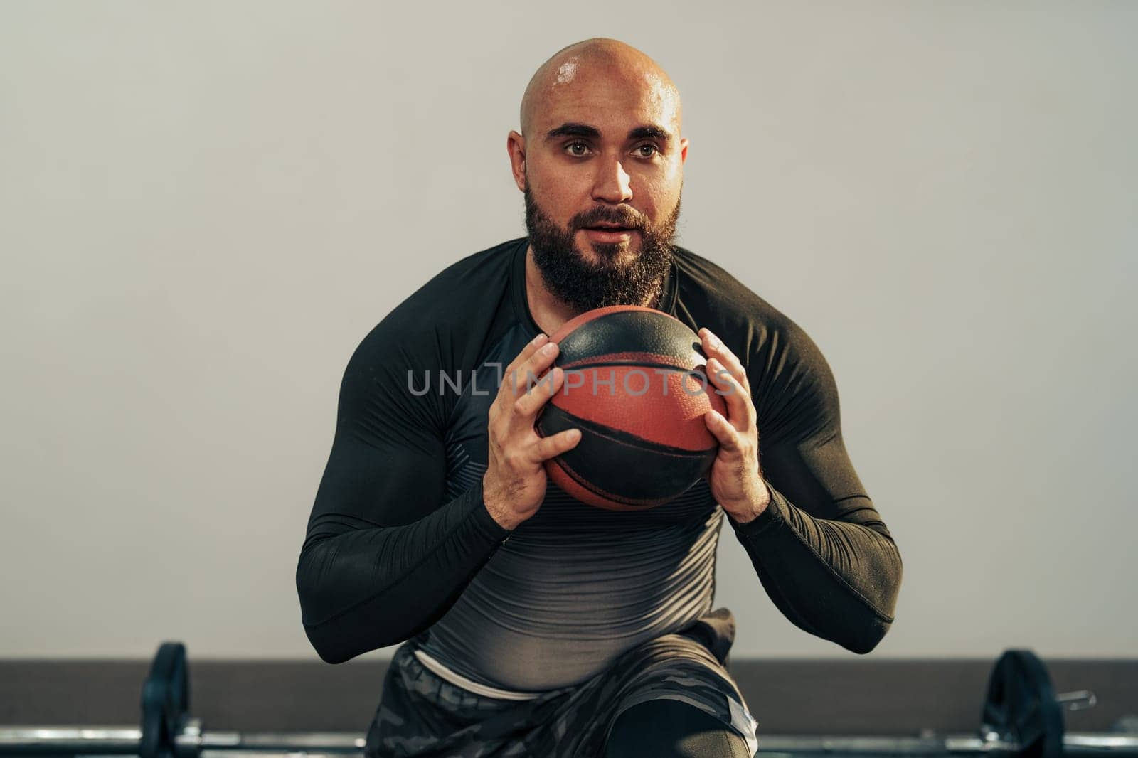 A focused individual performs an exercise with a medicine ball, displaying determination and strength. The gym atmosphere is energetic, filled with workout equipment.