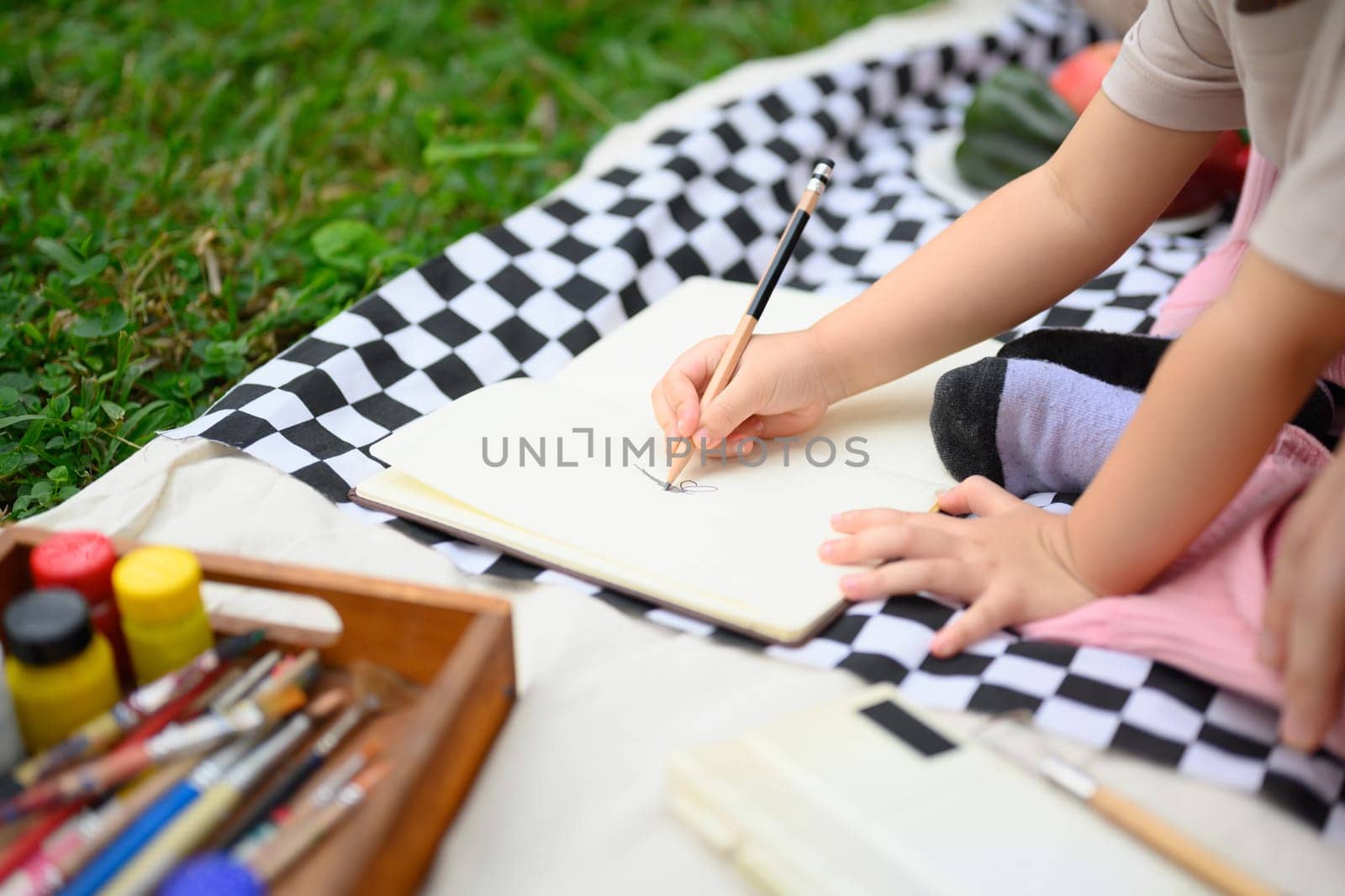Cropped shot of little girl drawing during a family picnic in a park.