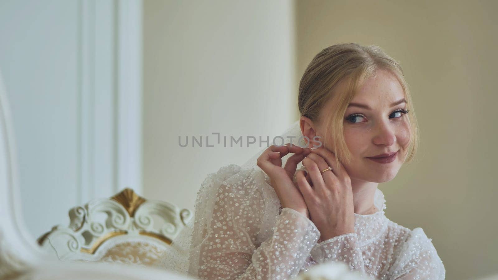 Beautiful bride adjusting delicate earrings, elegant white gown highlighting wedding day beauty and anticipation