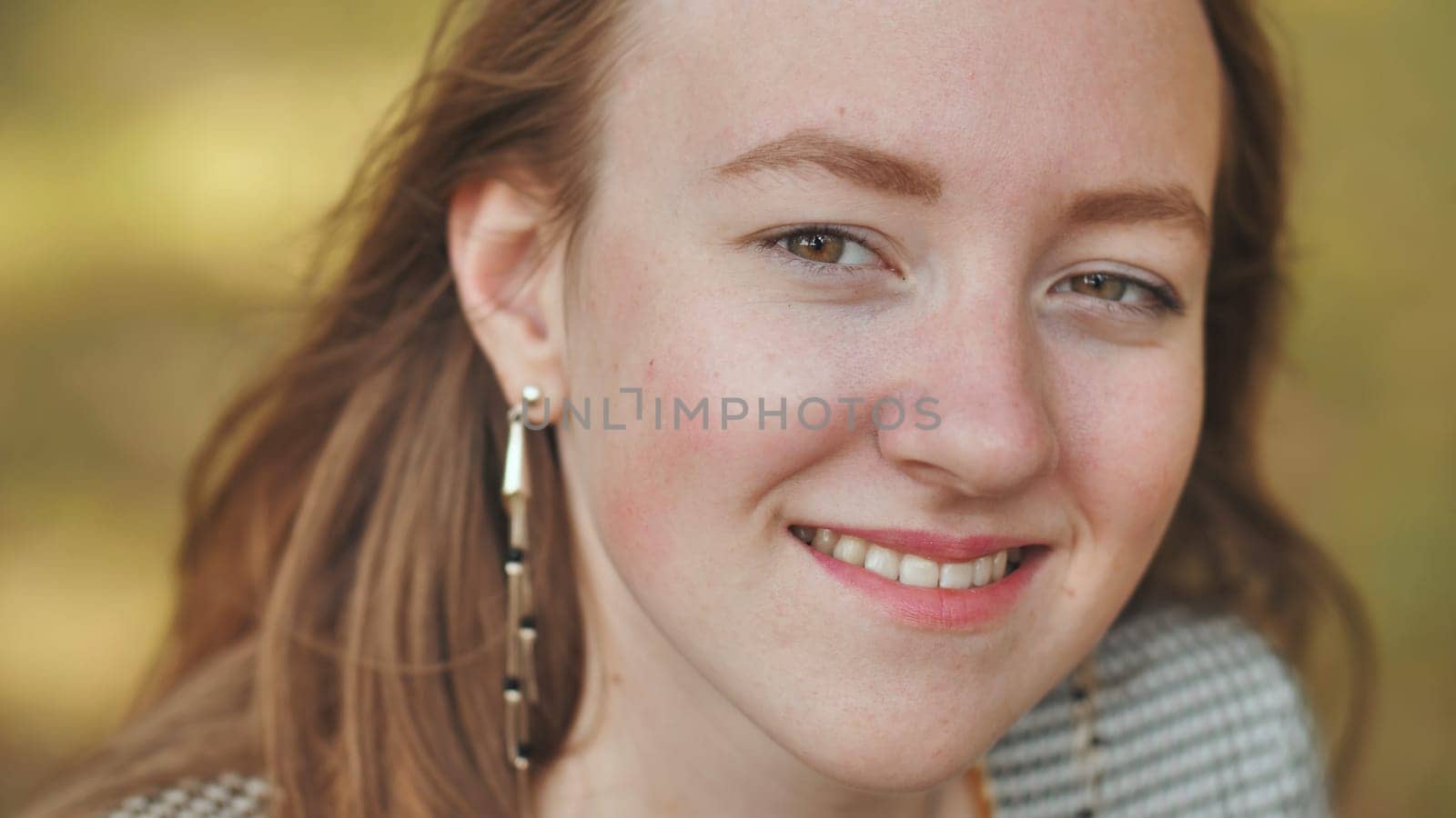 Close up portrait of a smiling young redhead woman with freckles, enjoying a moment of happiness and joy