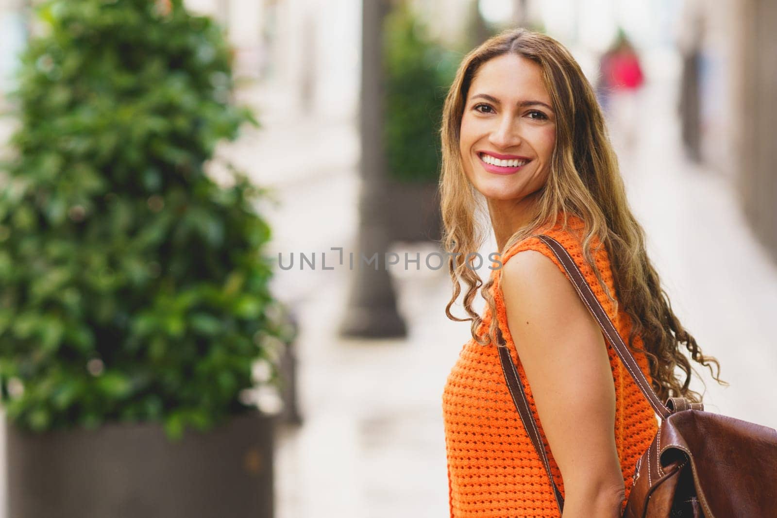 Happy latin woman turning to smile at camera walking in the city