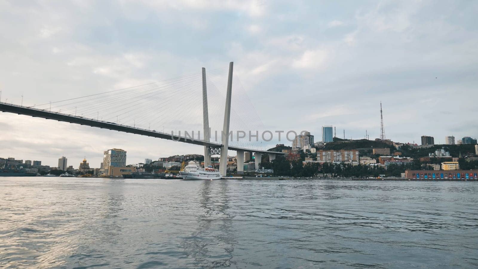 Offering a stunning view of the zolotoy rog bridge alongside the vibrant cityscape of vladivostok, framed by the serene waters of the sea