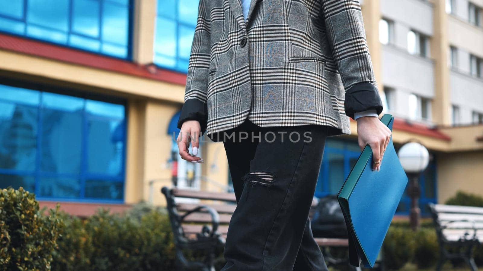 Office worker confidently walking through the urban street, carrying a blue folder filled with important documents for the day ahead