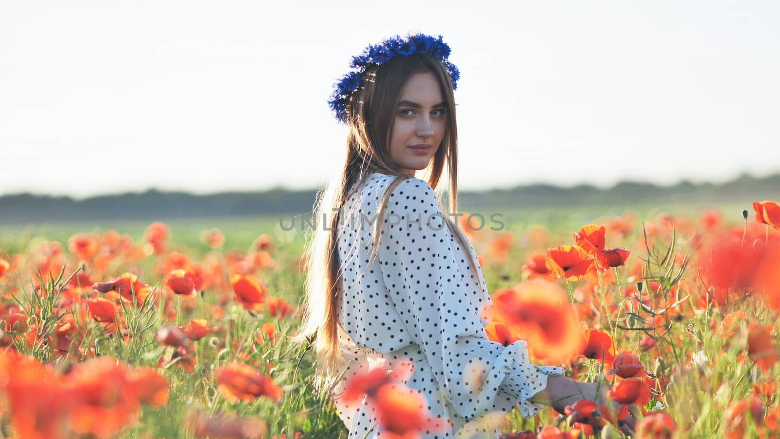 Slavic woman wearing flower crown, standing amid blooming poppies during golden sunset, embodying natural beauty and serene freedom