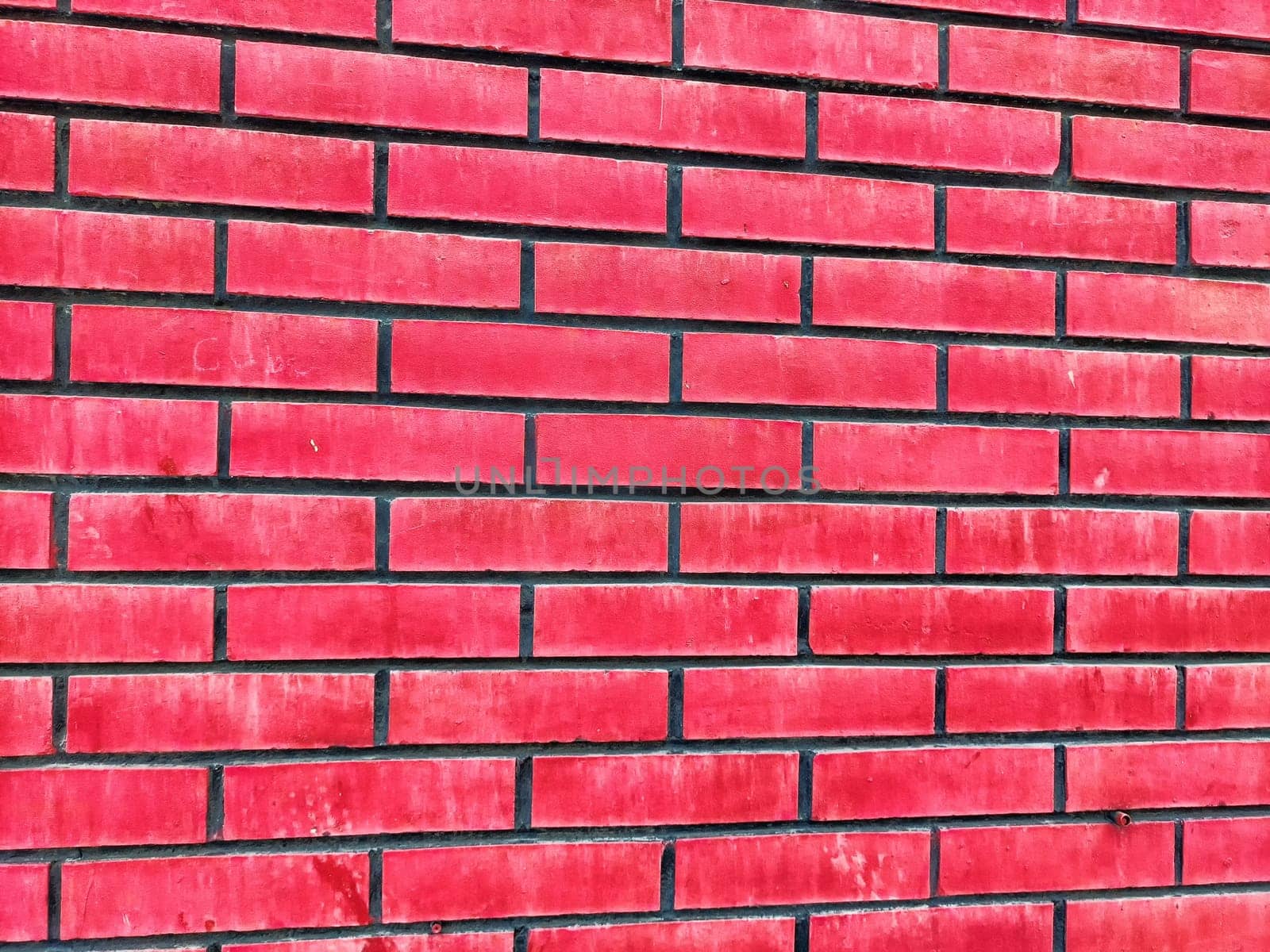 Vivid red brick wall showcases a structured pattern and provides ample copy space for customization or artistic projects.