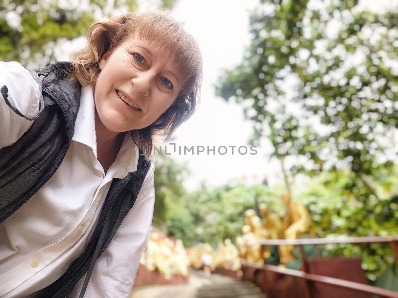 A traveler captures a selfie while exploring the lush surroundings of the 1000 Buddha Monastery in Hong Kong.