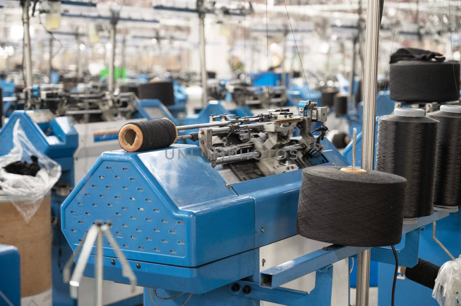 View of automated textile manufacturing machines in a factory, with spools of white thread ready for processing.