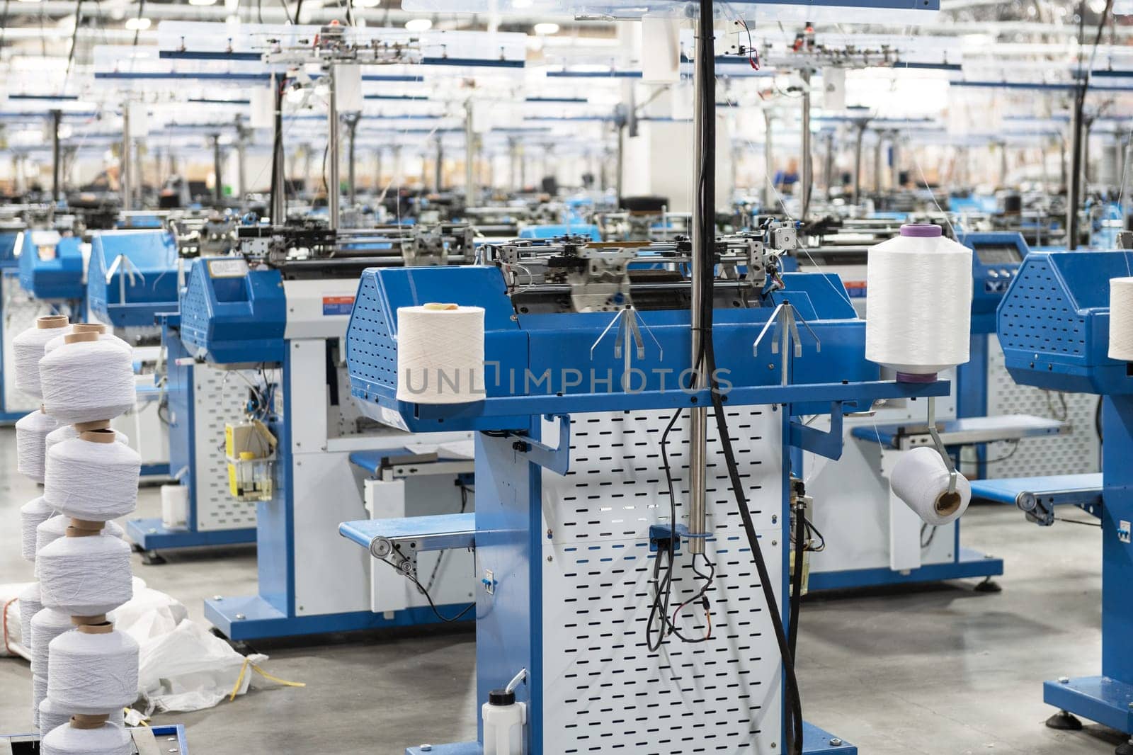 View of automated textile manufacturing machines in a factory, with spools of white thread ready for processing.